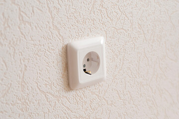 A white socket on the wall. Electricity equipment in interior.