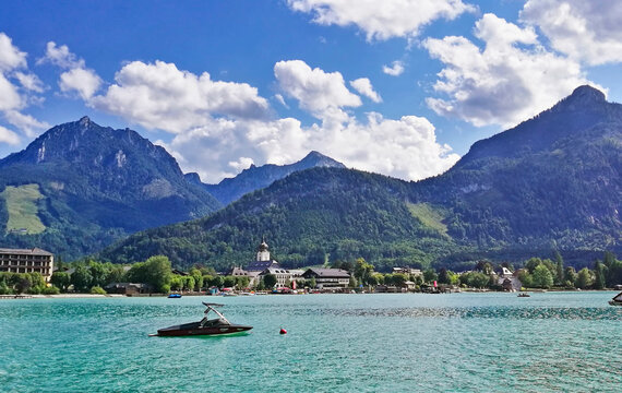 A boat in the middle of Wolfgangsee, with the mountains Sparber and Rettenkogel in the background.