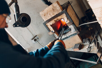 Blacksmith forge oven with hot flame. Smith put in and heating iron piece of steel in fire of red hot forge