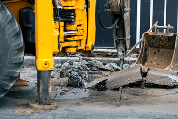 Heavy machinery removes the old layer of asphalt on a city street with a pneumatic jackhammer....