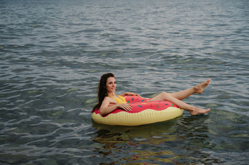 slender girl swims on an inflatable circle in sea in summer on vacation