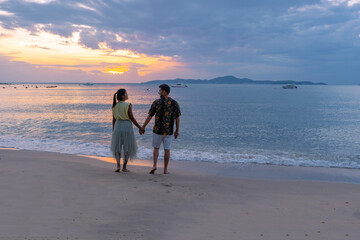 Sunset on Cosy Beach Pattaya Thailand, couple man, and woman walking on the beach during sunset in...