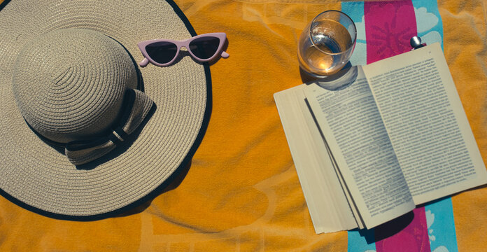 Summer holiday concept with yellow towel, sun hat, sunglasses and a book - Powered by Adobe