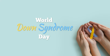 World Down syndrome day. Mom and baby are holding a blue and yellow ribbon in their hands.Down...