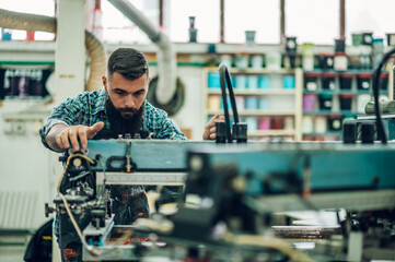 Fototapeta na wymiar Male worker using printing machine in a workshop