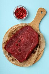 Concept of tasty food with raw beef steak on blue background