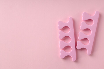 Pink nail separators on pink background, close up