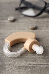Concept of health care with hearing aid on gray wooden background