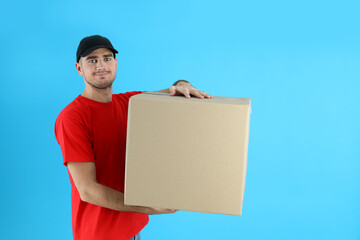 Delivery man holds box on blue background