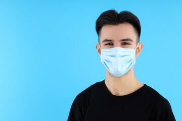 Young man in medical mask on blue background