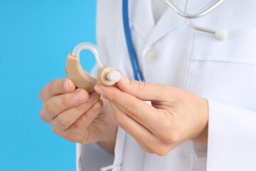 Doctor holding a hearing aid on a blue background