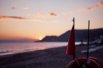Travel by Turkey. Red flag and safety buoy circe on the sea beach.