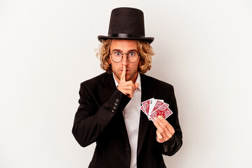 Young magician caucasian man holding magic cards isolated on white background keeping a secret or...