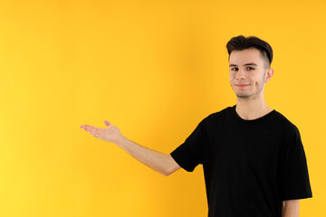 Attractive young man in t-shirt on yellow background