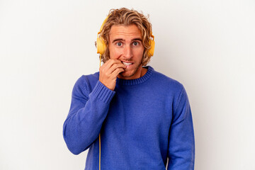 Young caucasian man listening to music isolated on white background biting fingernails, nervous and very anxious.