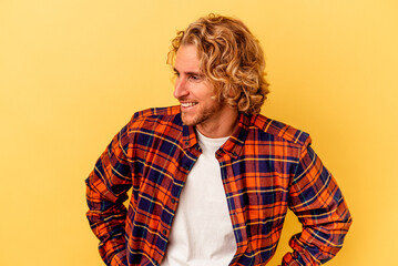 Young caucasian man isolated on yellow background laughs happily and has fun keeping hands on stomach.