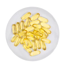 Foto op Plexiglas Lieve mosters Hoop pillen van visolie capsules geïsoleerd op een witte plaat. Bovenaanzicht.
