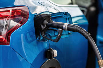 car fueling at gas station, petrol pump filling fuel nozzle in fuel tank of car at gas station