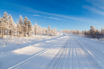 The road climbs the mountain in the winter forest