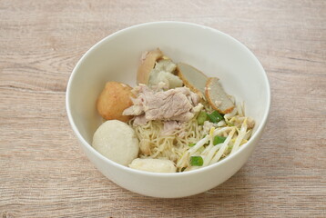 dry egg yellow noodles noodles topping slice boiled pork and ball on bowl