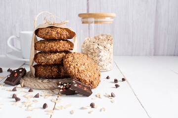 Homemade oatmeal cookies with chocolate and nuts tied with jute thread on baking paper and white wooden background