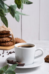 A cup of coffee in the foreground. Selective focus. Against the background of oatmeal cookies