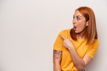 Young caucasian woman isolated on white background points with thumb finger away, laughing and carefree.