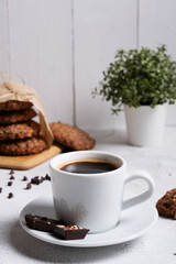 A cup of coffee in the foreground. Selective focus. Against the background of oatmeal cookies
