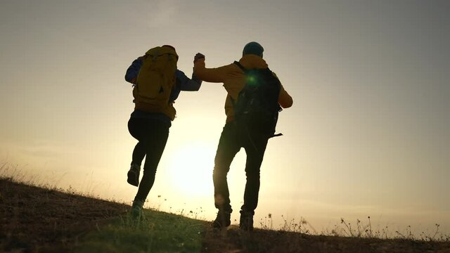 business teamwork a freedom concept. couple of tourists run with silhouette backpacks running jumping. travel freedom business concept. couple teamwork hikers running jumping sunset