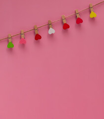 Wooden clothespins with colorful hearts on a rope on a pink background. Composition for Valentine's Day. Flat lay, copy space. Greeting card. 