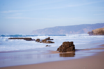 Beautiful seascape. Sand beach with rocks and big waves.