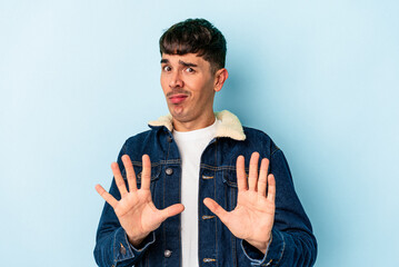 Young mixed race man isolated on blue background rejecting someone showing a gesture of disgust.