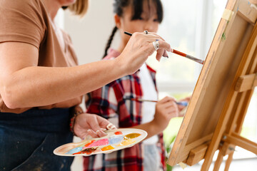 Mature teacher drawing with her pupil during class in art school