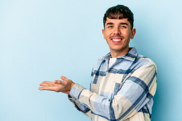 Young mixed race man isolated on blue background holding a copy space on a palm.