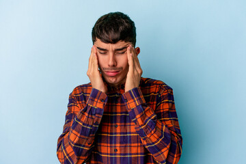 Young mixed race man isolated on blue background having a head ache, touching front of the face.