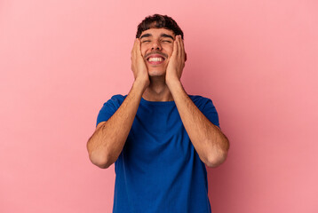 Young mixed race man isolated on pink background laughs joyfully keeping hands on head. Happiness concept.