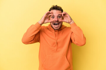 Young caucasian man isolated on yellow background keeping eyes opened to find a success opportunity.