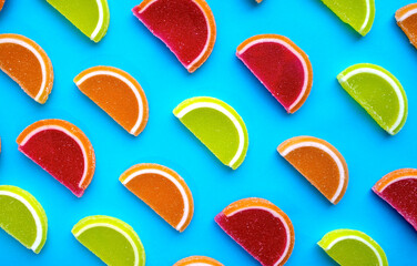 Colorful oval citrus jelly candies pattern on a blue background. Yellow, pink, red, orange round shaped marmalade.