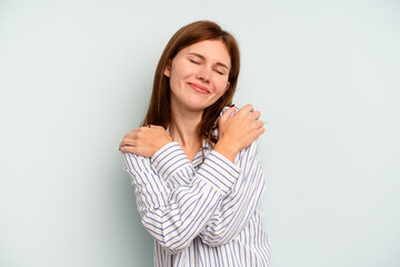 Young English woman isolated on blue background hugs, smiling carefree and happy.