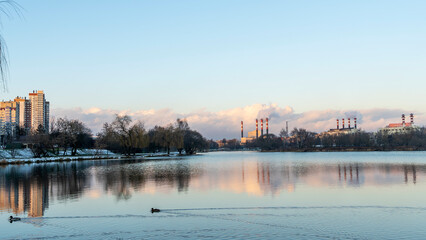 Fototapeta premium Smoking chimneys of a thermal power plant against a winter cloudy sky. Ecological problems concept. Space for text.
