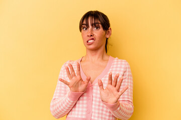 Young Argentinian woman isolated on yellow background rejecting someone showing a gesture of disgust.