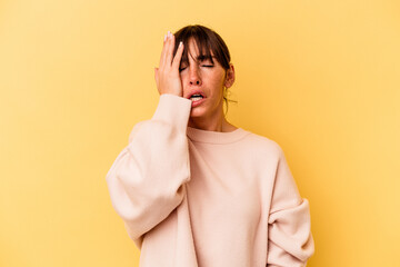 Young Argentinian woman isolated on yellow background tired and very sleepy keeping hand on head.