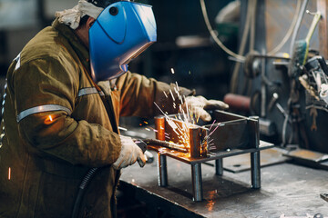 Welder welding metal steel industrial part construction on factory.