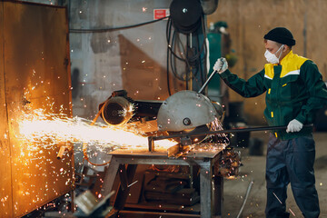 Metal processing with big angle grinder disk saw. Sparks in metalworking at factory worker