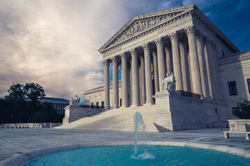 Blue fountain spouting water in plaza with steps to entrance of United States Supreme Court...