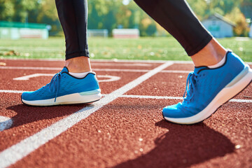 Male runner feet with blue sneakers stadium track, close up. Sport sneakers for jogging. Fitness and healthy lifestyle concept