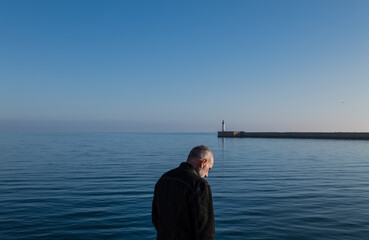 Fototapeta premium Adult man against sea and sky with lighthouse in background. Almeria, Spain
