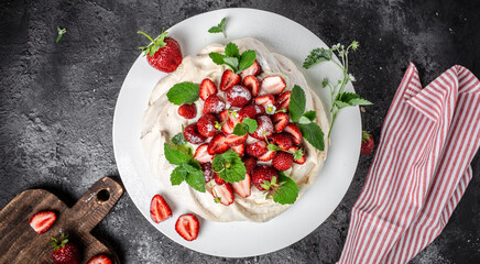 delicious homemade Pavlova cake with fresh strawberries and whipped cream. Female baker decorating delicious meringue cake, top view. place for text