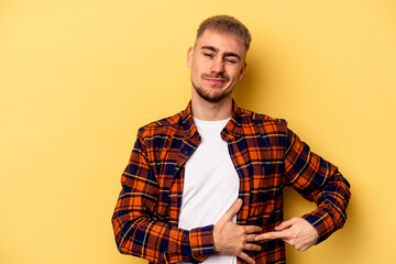 Young caucasian man isolated on yellow background having a liver pain, stomach ache.
