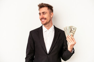 Young caucasian business man holding bank notes isolated on white background looks aside smiling, cheerful and pleasant.